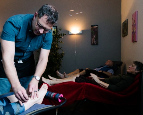 Several people relaxing after receiving acupuncture. Acupuncturist removes needles from a patient in the foreground