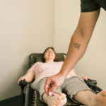 an acupuncturist puts a needle into a patients ankle