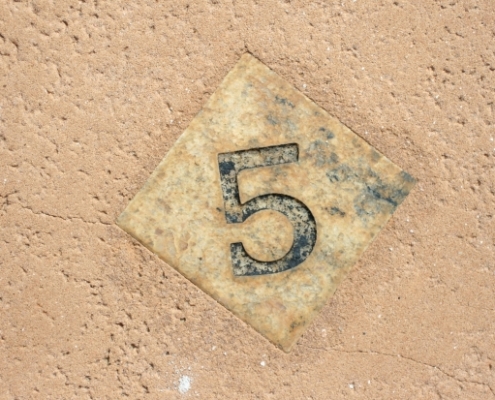 A wooden tile with the number 5 on it.