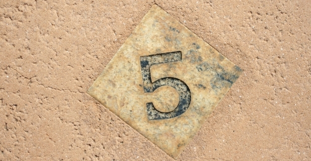 A wooden tile with the number 5 on it.